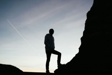 silhouette of man standing on rock during sunset